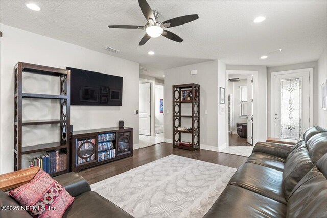 living room featuring ceiling fan, visible vents, wood finished floors, baseboards, and recessed lighting