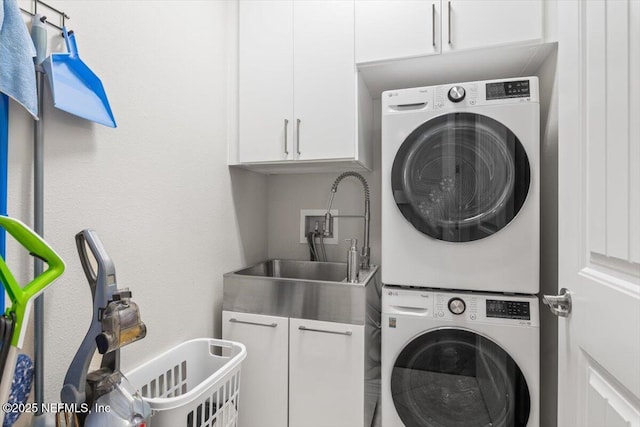 laundry room with a sink, cabinet space, and stacked washer / dryer