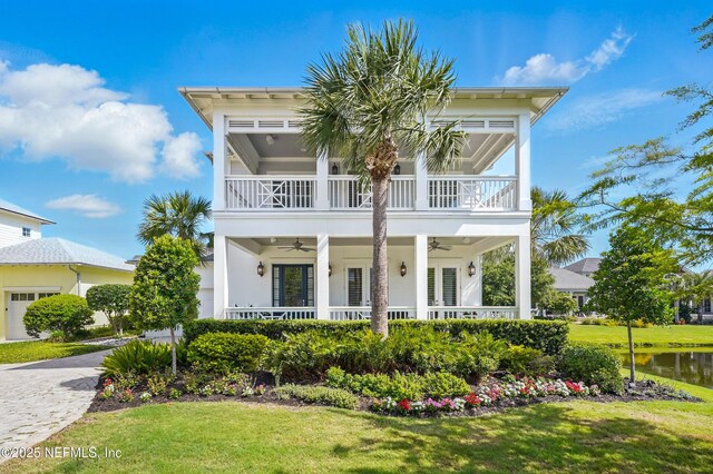 view of front facade with a front lawn, a porch, decorative driveway, a balcony, and a ceiling fan