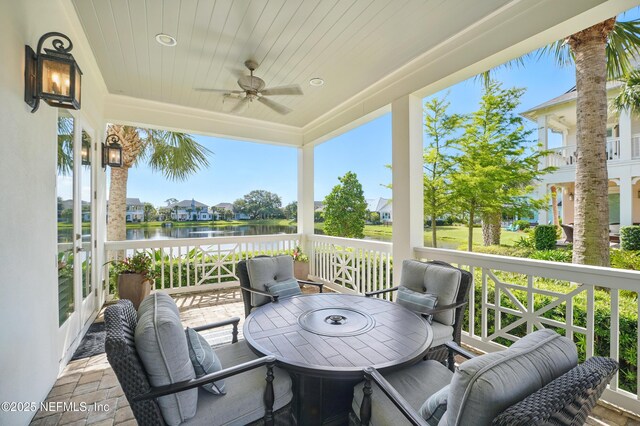 wooden deck with a water view, a ceiling fan, a residential view, and outdoor dining space