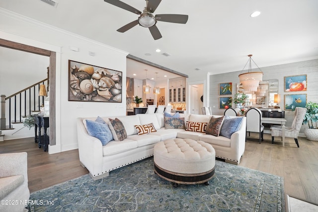 living area featuring a ceiling fan, wood finished floors, stairway, ornamental molding, and recessed lighting