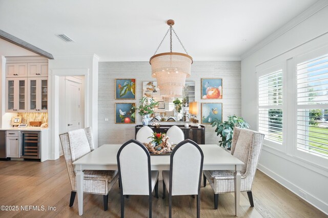 dining space featuring visible vents, wine cooler, light wood-style floors, baseboards, and a chandelier