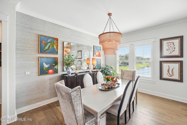 dining area featuring baseboards, a chandelier, wood finished floors, and an accent wall
