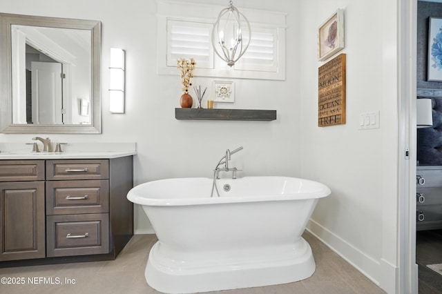 bathroom with a freestanding tub, baseboards, vanity, and tile patterned floors
