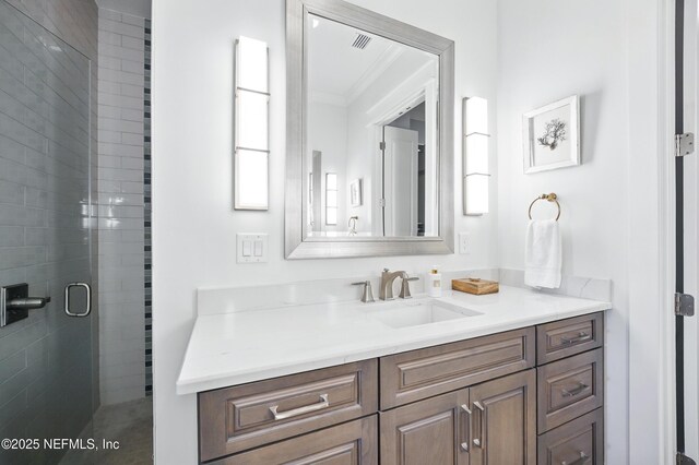 full bath featuring vanity, visible vents, ornamental molding, and a stall shower