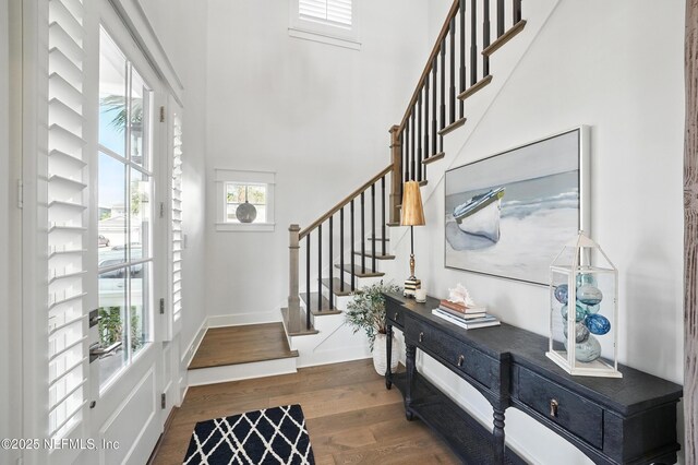 entrance foyer with a high ceiling, stairs, and wood finished floors