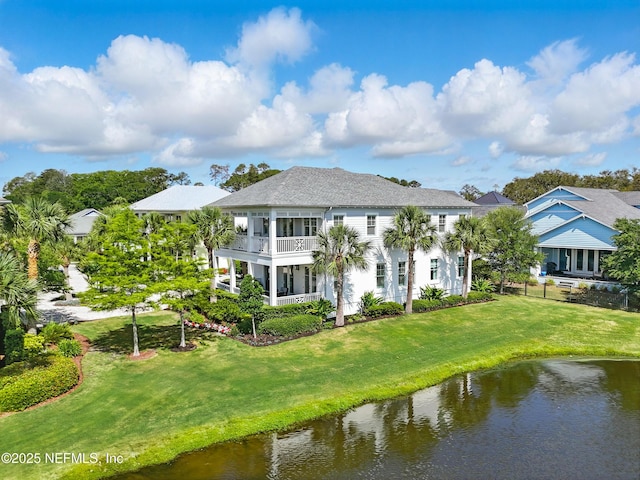 rear view of property with a lawn, fence, a water view, and a balcony