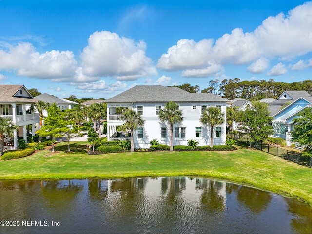 rear view of house with fence, a water view, and a residential view