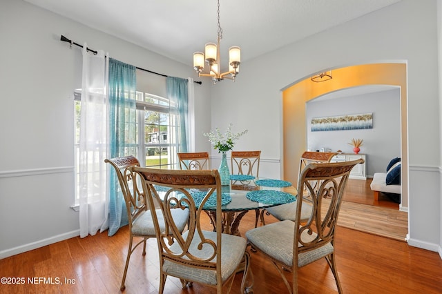 12139 Cap Ferrat St, Jacksonville, FL 32224 - dining room with a chandelier, arched walkways, baseboards, and light wood-style floors