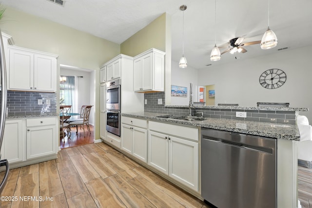12139 Cap Ferrat St, Jacksonville, FL 32224 - kitchen with a peninsula, light wood-style flooring, a ceiling fan, stainless steel appliances, and white cabinets