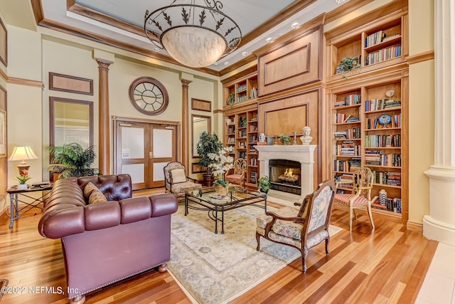 400 E Bay St Unit 1610-1611, Jacksonville, FL 32202 - living area with a warm lit fireplace, built in shelves, light wood-style flooring, ornate columns, and ornamental molding