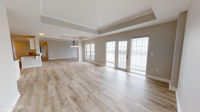 400 E Bay St Unit 1610-1611, Jacksonville, FL 32202 - unfurnished living room featuring baseboards, light wood-style flooring, a raised ceiling, and a notable chandelier