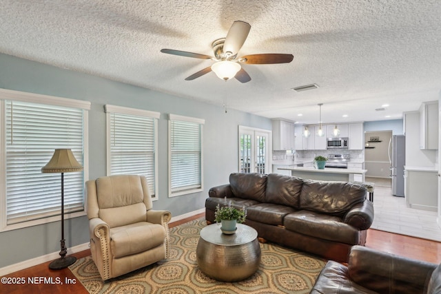 5914 Orchard Pond Dr, Fleming Island, FL 32003 - living area featuring a ceiling fan, a textured ceiling, and baseboards