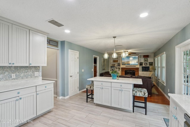 5914 Orchard Pond Dr, Fleming Island, FL 32003 - kitchen featuring a breakfast bar, open floor plan, a ceiling fan, decorative backsplash, and light countertops