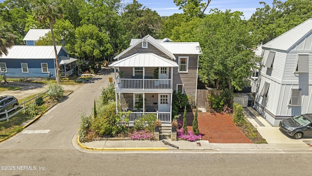 120 Washington St, Saint Augustine, FL 32084 - view of front of property with a balcony, stone siding, a standing seam roof, metal roof, and a porch