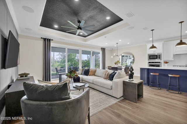 568 Blind Oak Cir, Saint Augustine, FL 32095 - living room featuring visible vents, ornamental molding, light wood-type flooring, a raised ceiling, and a ceiling fan