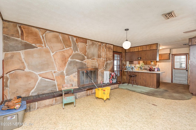 kitchen featuring brown cabinetry, pendant lighting, a peninsula, and visible vents