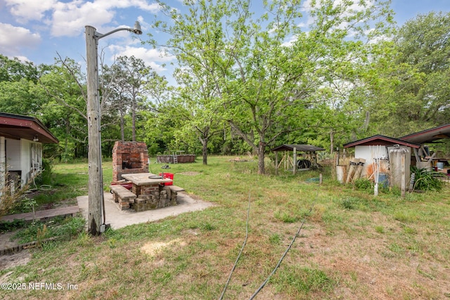 view of yard with an outdoor structure, exterior fireplace, and a shed