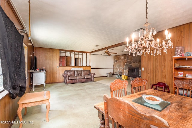 dining area featuring baseboards, wood walls, and ceiling fan with notable chandelier