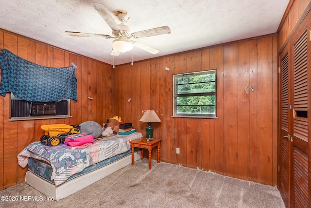 carpeted bedroom featuring a textured ceiling, ceiling fan, wood walls, and cooling unit