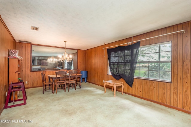 dining room featuring baseboards, wood walls, and a notable chandelier