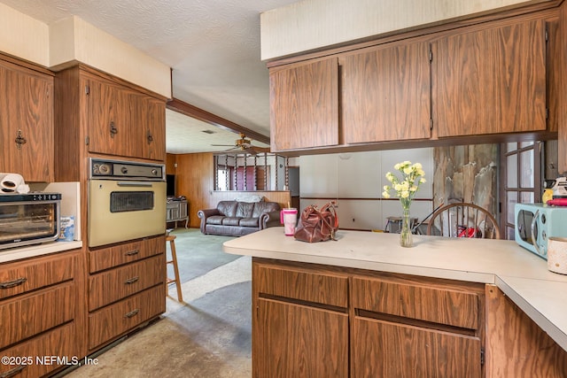 kitchen with ceiling fan, white oven, light countertops, open floor plan, and carpet