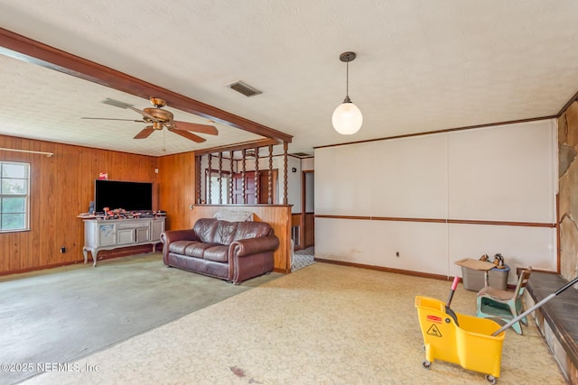 living room with visible vents, baseboards, ceiling fan, and wooden walls