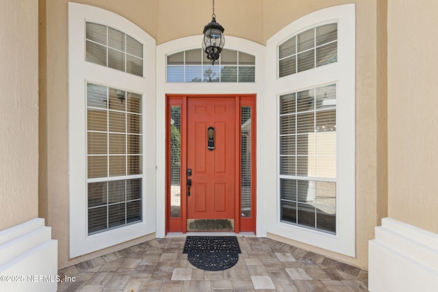doorway to property with covered porch and stucco siding