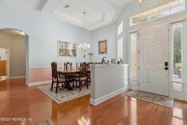 entrance foyer with arched walkways, visible vents, hardwood / wood-style flooring, and a notable chandelier
