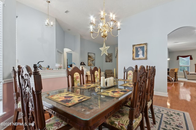 dining room featuring arched walkways, wood finished floors, and a notable chandelier