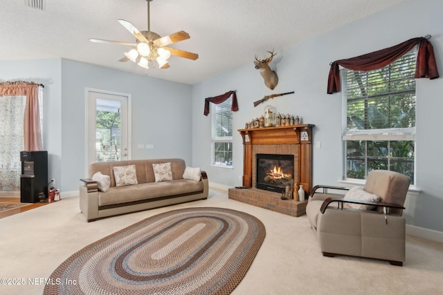 living area with a fireplace, baseboards, ceiling fan, a textured ceiling, and carpet flooring