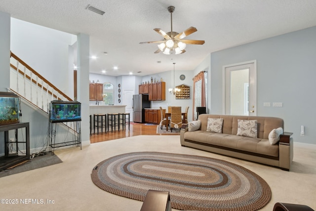 living area with visible vents, stairs, ceiling fan, and light colored carpet