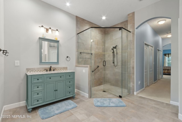 bathroom featuring vanity, baseboards, and a stall shower