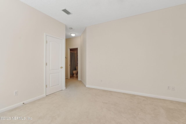 spare room with visible vents, baseboards, and light carpet
