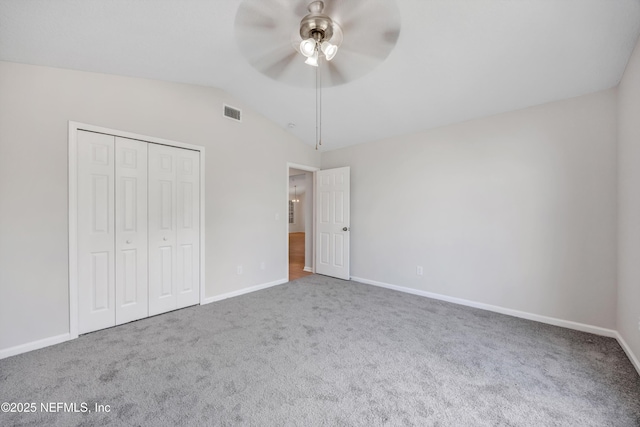 unfurnished bedroom featuring baseboards, carpet, lofted ceiling, and visible vents