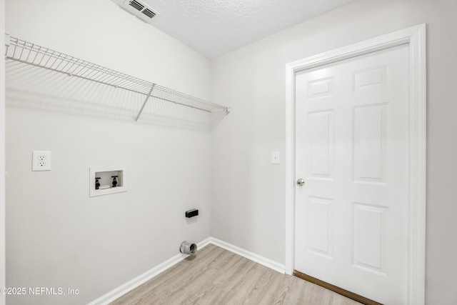 laundry area with laundry area, visible vents, baseboards, hookup for a washing machine, and light wood-style flooring