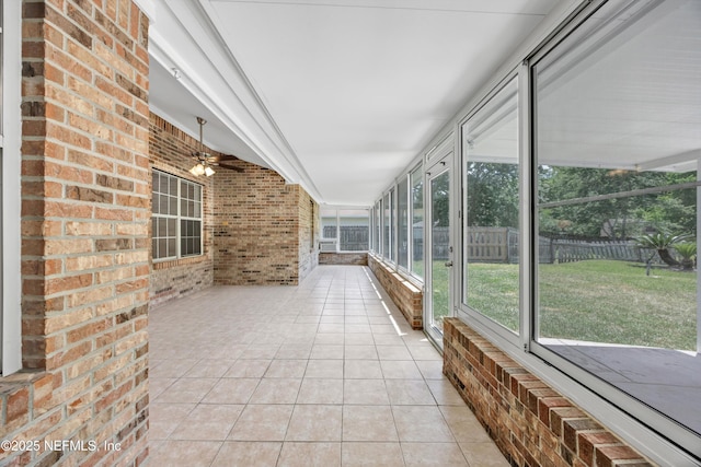 unfurnished sunroom with ceiling fan