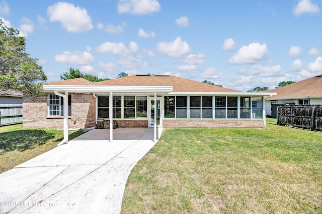 exterior space featuring brick siding, a front yard, fence, and a sunroom