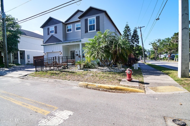 view of front of home featuring board and batten siding, fence, a garage, and driveway