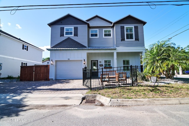 view of front of house featuring a porch, a fenced front yard, a garage, and decorative driveway