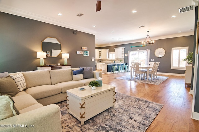 living area featuring light wood finished floors, visible vents, ornamental molding, and recessed lighting