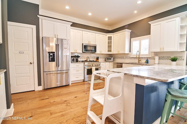 kitchen with a peninsula, a breakfast bar, open shelves, stainless steel appliances, and ornamental molding