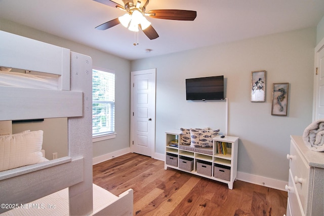 living area featuring wood finished floors, baseboards, and a ceiling fan