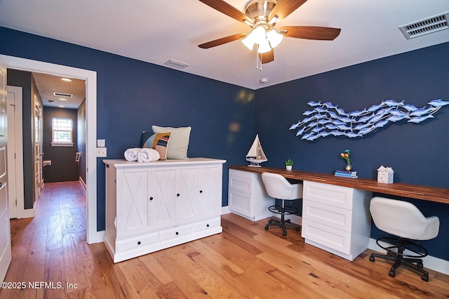 office area with light wood finished floors, visible vents, baseboards, and a ceiling fan