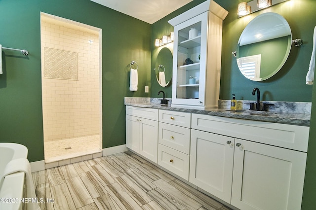 full bathroom featuring double vanity, baseboards, tiled shower, and a sink