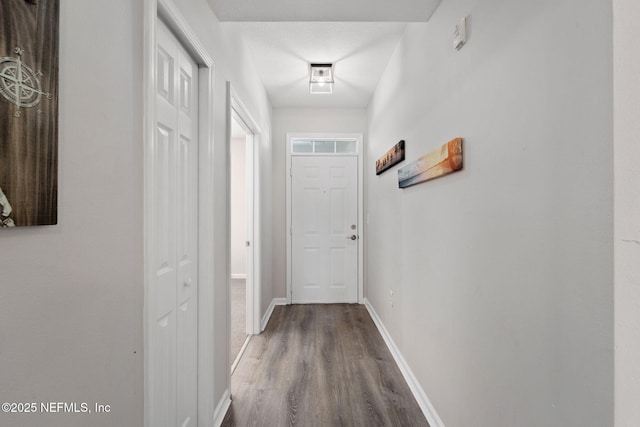 corridor featuring baseboards and wood finished floors