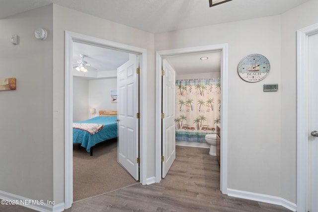 hallway featuring baseboards and wood finished floors