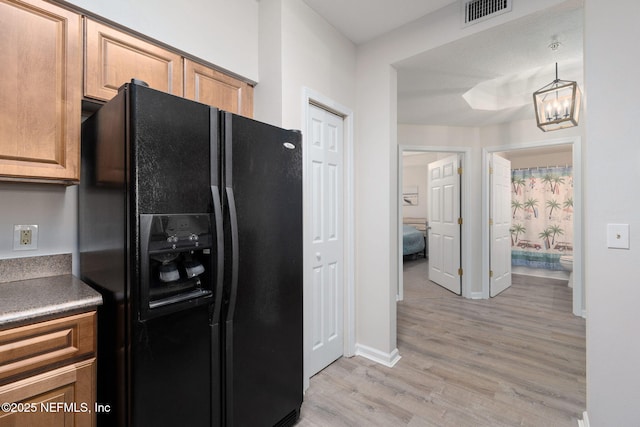 kitchen featuring visible vents, light wood-type flooring, baseboards, an inviting chandelier, and black fridge