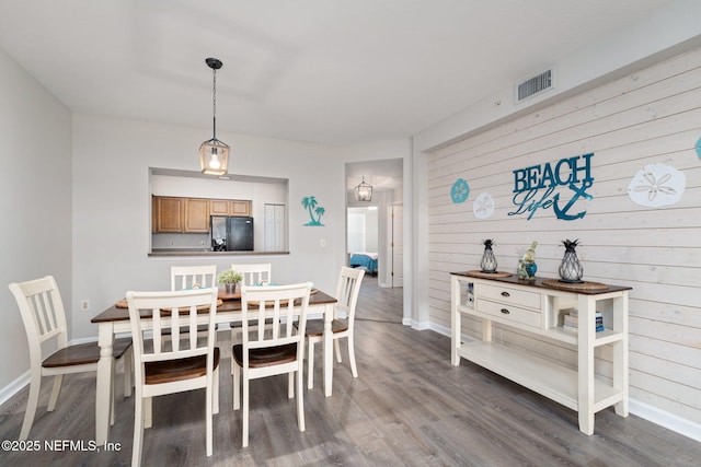 dining space with baseboards, visible vents, and wood finished floors