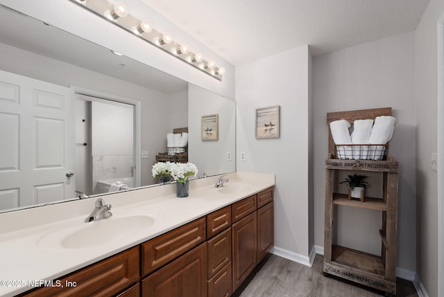 full bathroom featuring double vanity, a sink, wood finished floors, and a tub